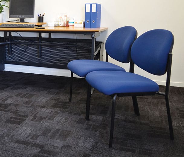 Blue Buro Essence visitor chairs alongside an office desk
