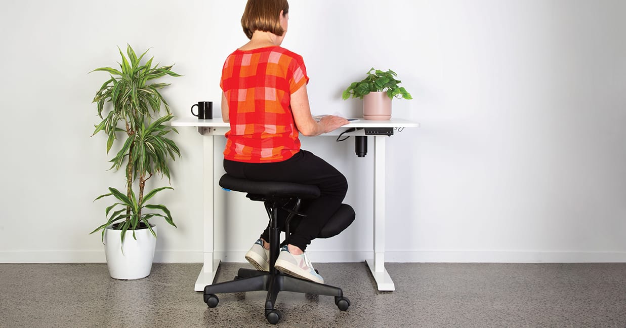 Lady sitting on a Buro Knee chair in a home office scene with Mondo Lypta desk