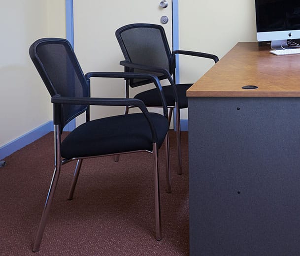 Two Buro Lindis Mesh back visitor chairs next to an office desk 