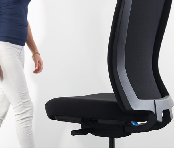 Detail view of woman standing next to a Buro Mentor ergonomic task chair with upholstered back