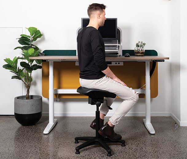 Man seated on Buro Posturite stool at an office desk
