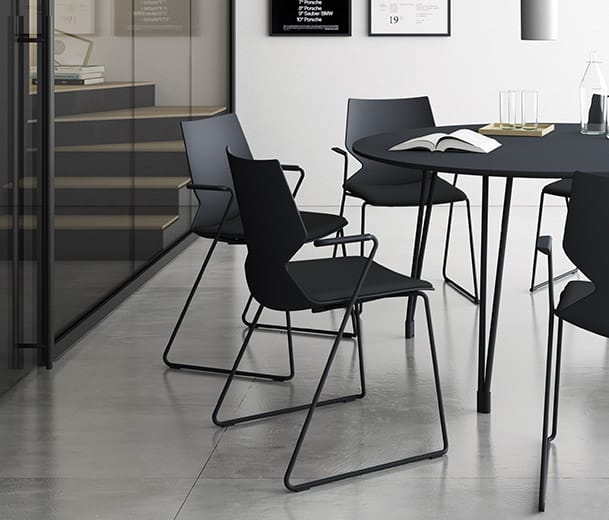 Black Konfurb Fly Sled chairs with arms around a Konfurb Fly table in a collaborative office space